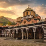 Rila Monastery, one of the top things to do in Bulgaria, framed by mountains at golden hour
